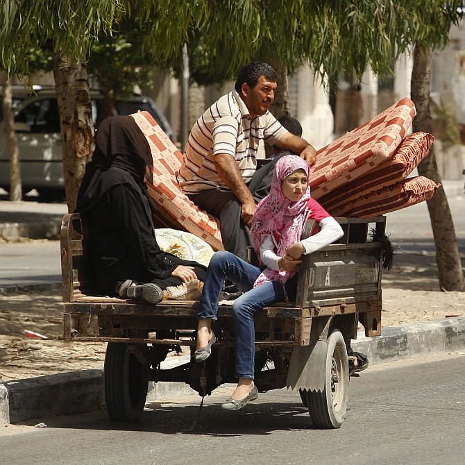 Palestinians, who fled their homes that are adjacent to the border with Israel, ride a motorised rickshaw as they make their way to stay at a United Nations-run school, in the northern Gaza Strip