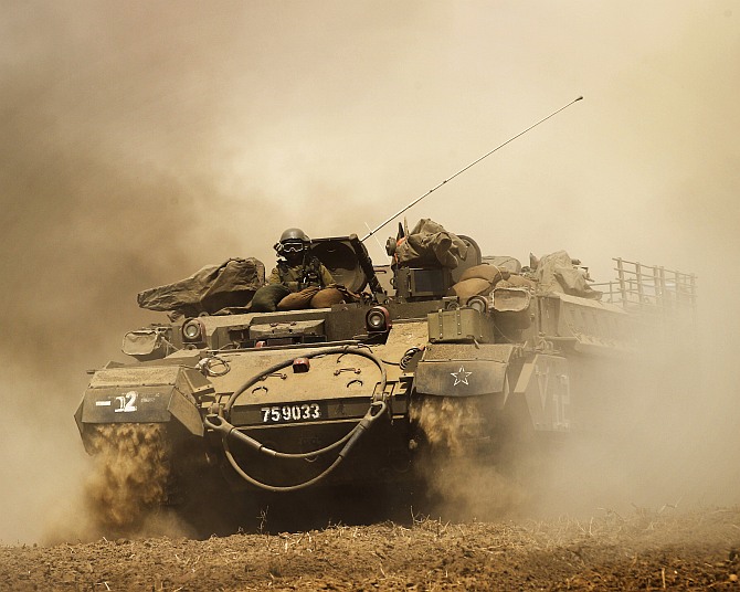 An Israeli armoured vehicle drives across a field near central Gaza Strip