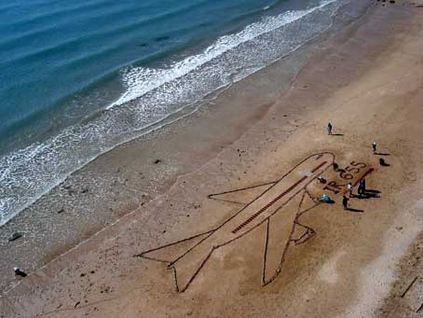 Remembering the tragedy, children draw a plane with IR 655 below it on the sand. 