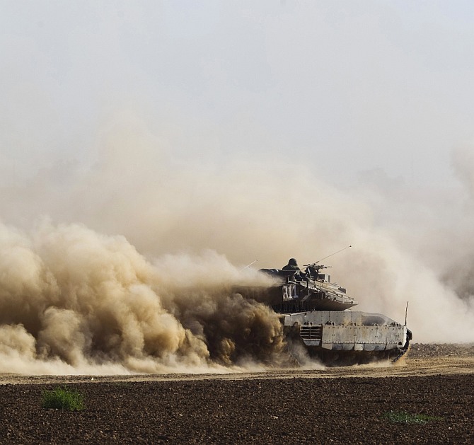 An Israeli soldier sits atop an armoured personnel carrier (APC) as it drives after the end of a five-hour humanitarian truce, near the border with the Gaza Strip
