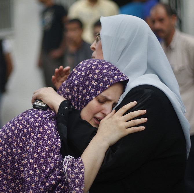 The mother (C) of two boys from the Shaibar family, whom medics said were killed along with a girl from the same extended family by an Israeli air strike after the end of a five-hour humanitarian ceasefire, grieves during their funeral outside a hospital morgue in Gaza City 
