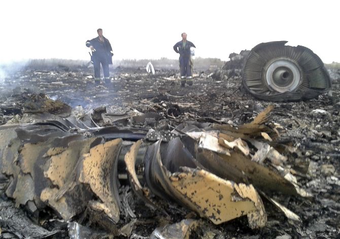 Officials overlook the debris of downed flight MH17 after it went down on Thursday evening. 