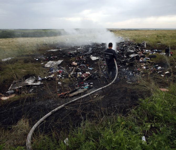 Officials pour water on the burning debris of Flight MH17