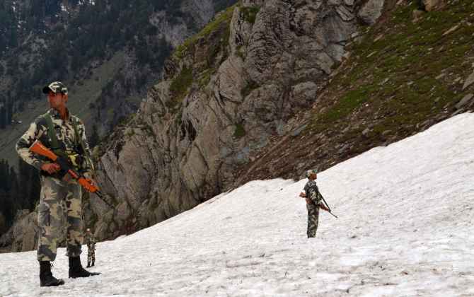 Security personnel guard the hills as pilgrims proceed to the Holy Amarnath cave from Baltel route on Saturday