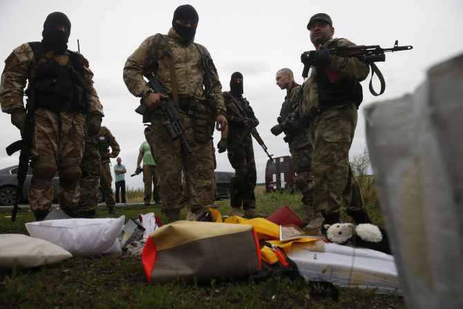 Pro-Russian separatists look at passengers' belongings at the crash site