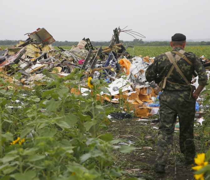 A pro-Russian separatist looks at wreckage from the nose section of a Malaysia Airlines Boeing 777 plane which was downed near the village of Rozsypne, in the Donetsk region of Ukraine.