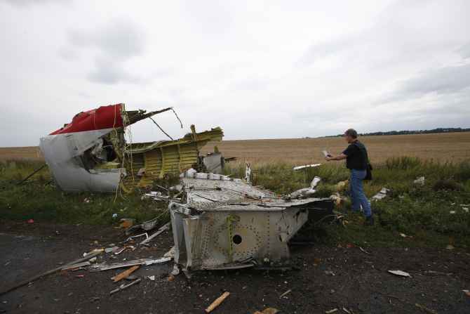 An Organisation for Security and Cooperation in Europe monitor takes a photograph at the crash site of Malaysia Airlines flight MH17, near the settlement of Grabovo