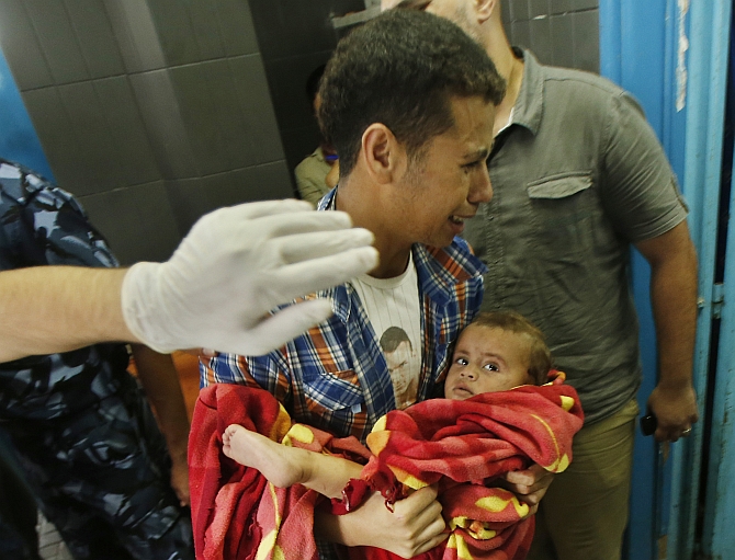 A Palestinian man reacts as he carries a boy, who medics said was wounded in Israeli shelling, at a hospital in Gaza City