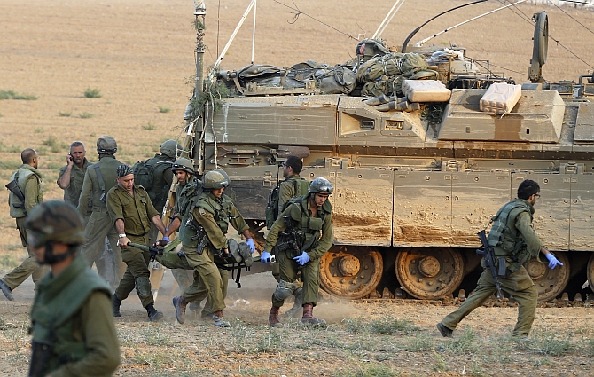 Israeli soldiers carry a comrade on a stretcher, who was wounded during an offensive in Gaza, outside northern Gaza