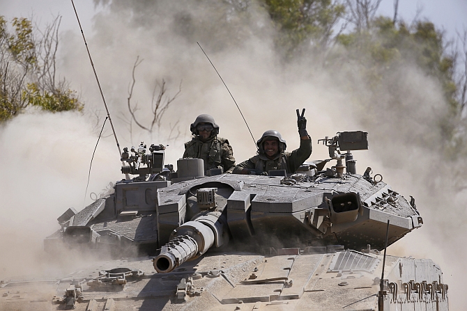  An Israeli soldier gestures from a tank near the border with Gaza