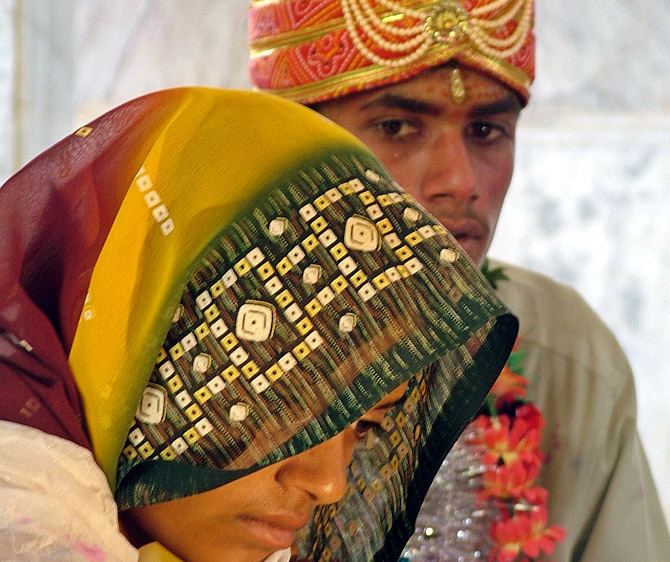 A young bride and groom sit in a temple during their marriage ceremony at a temple in Rajgarh district, Bhopal