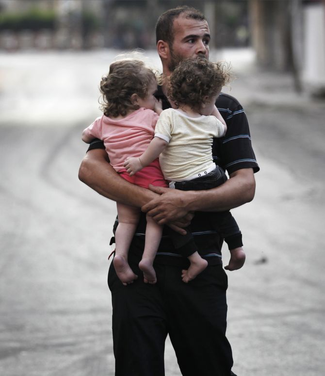A Palestinian man carrying children flees the Shujayeh neighbourhood in a vehicle during heavy Israeli shelling in Gaza.