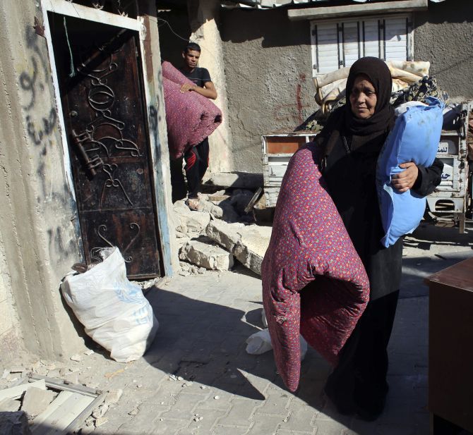 A Palestinian woman carries belongings as she flees her house, in Rafah in the southern Gaza Strip 