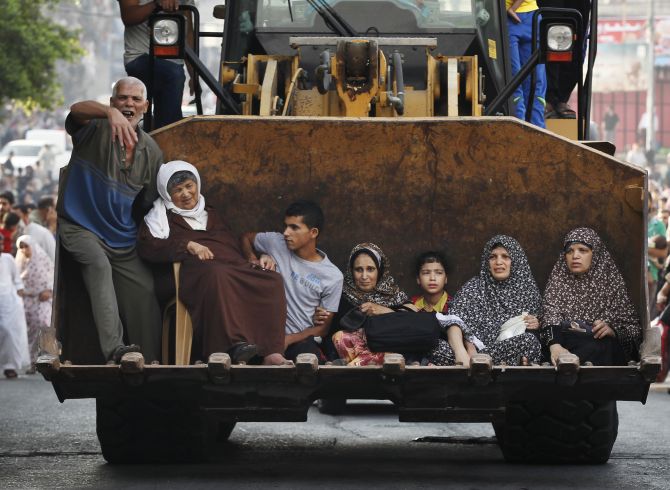 Palestinians sit in the bucket of an excavator as families flee the Shujayeh neighbourhood during heavy Israeli shelling in Gaza city. 