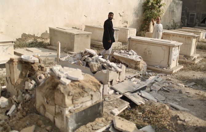 Palestinians inspect a cemetery which police said was damaged in Israeli shelling, in Gaza City