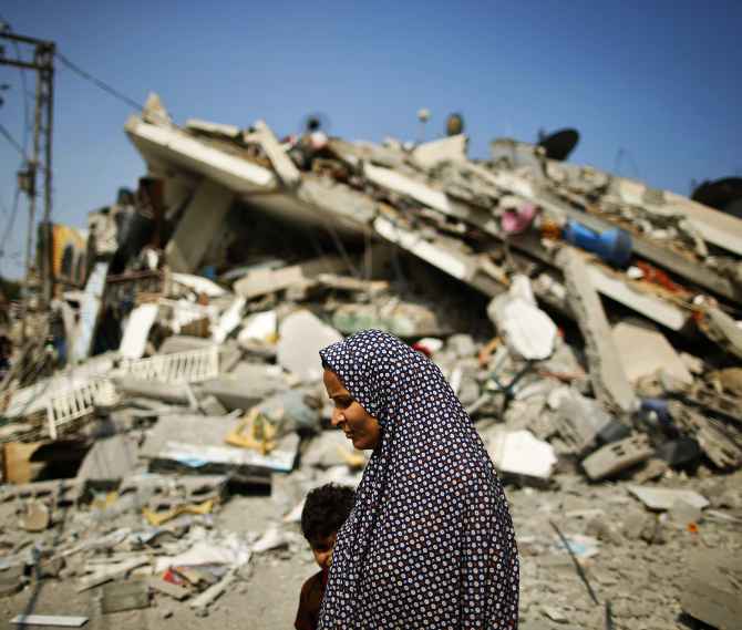 A Palestinian woman walks past the rubble of a residential building destroyed in an Israeli air strike in Gaza City.