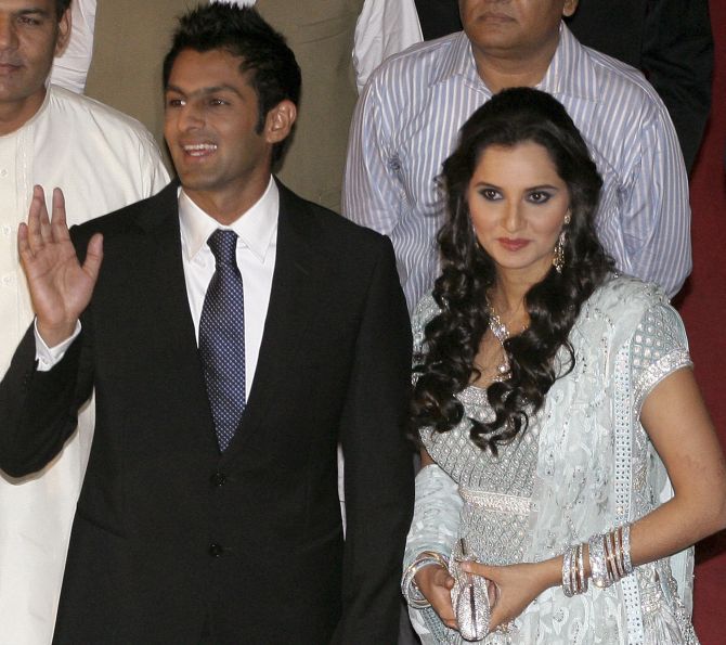 Pakistani cricketer Shoaib Malik with his wife, Indian tennis stars Sania Mirza, as they pose for photographs during their wedding reception in Lahore