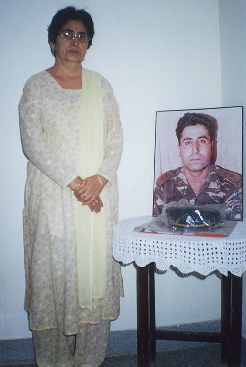 Kamal Batra with a picture of Vikram. His cap and the Indian flag that had wrapped his body is kept in front.