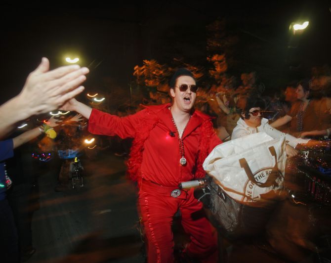 A member of the Krewe of Rolling Elvi, a local group who loves to dressed as Elvis Presley, rides a motorbike.