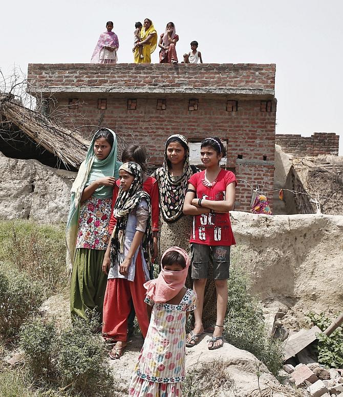 Villagers stand as they watch the house of one of the two teenage girls, who were raped and hanged from a tree, at Budaun district in UP