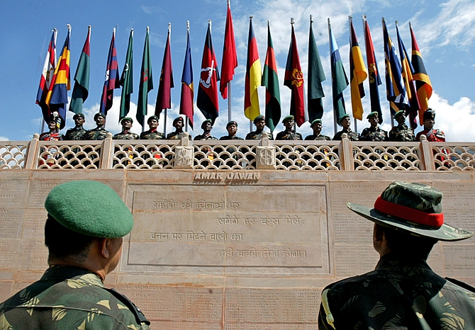Senior Indian army officers look at a wall with names of killed colleagues as soldiers stand under their regimental flags during during 'Vijay Diwas' celebrations in Drass