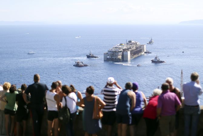 People watch the cruise liner Costa Concordia moving anticlockwise during the refloat operation maneuvers at Giglio Island. 
