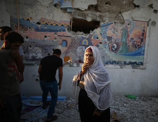 A Palestinian woman looks on as she stands at a United Nations-run school sheltering Palestinians displaced by an Israeli ground offensive, that witnesses said was hit by Israeli shelling, in Jebalya refugee camp in the northern Gaza Strip 