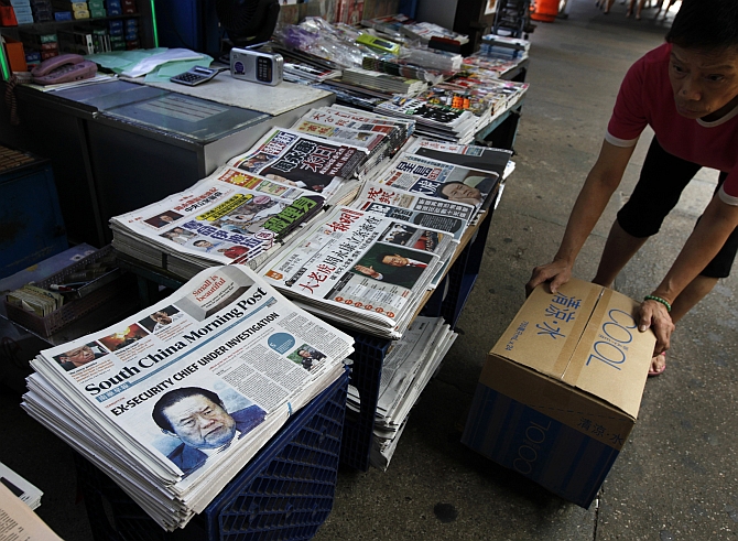  A vendor works beside Hong Kong newspapers showing photos of China's then Politburo Standing Committee Member Zhou Yongkang displayed at a newsstand in Hong Kong