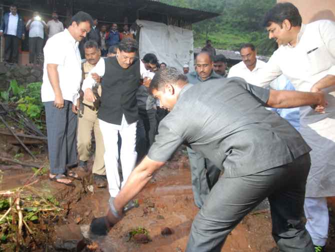 Maharashtra CM Prithviraj Chavan makes his way through the slush at the site of a landlside near Pune on Wednesday