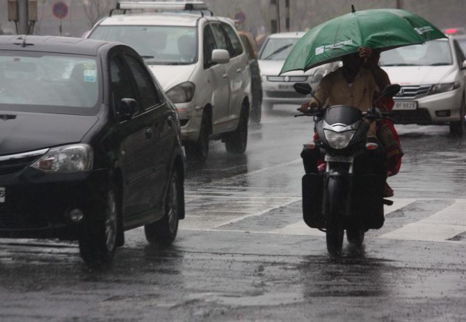A pillion rider tries to shield himself from the heavy downpour in Mumbai