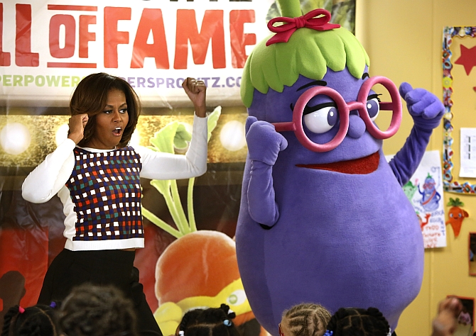 US First Lady Michelle Obama dances with an eggplant from the Super Sprowtz at a La Petite Academy chid care center in Bowie, Maryland