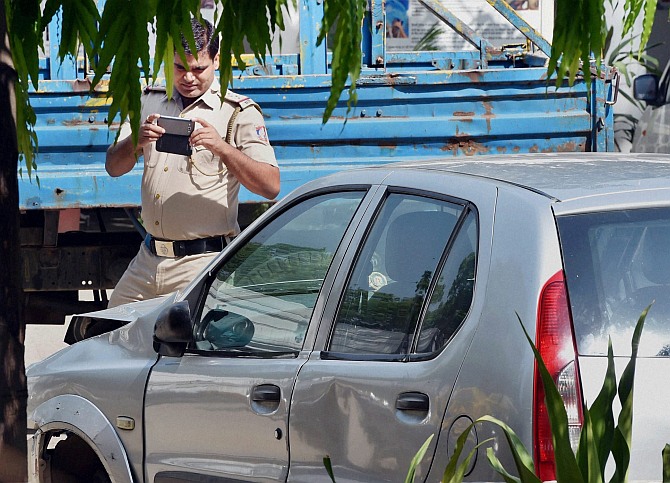 A police official takes photograph of the Indica car at Tuglak Road police station which hit Rural Development Minister, Gopinath Munde's car leading to his death