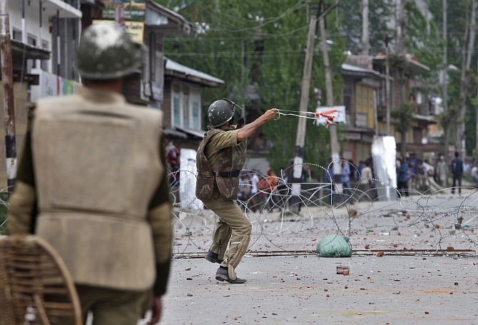 A policeman throws a stone towards Kashmiri protesters during an anti-election protest in Baramulla district, north of Srinagar