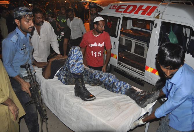 An Airport Security Force soldier (L) leads a colleague on a stretcher, who was wounded in an attack at Jinnah International Airport, outside Jinnah hospital in Karachi