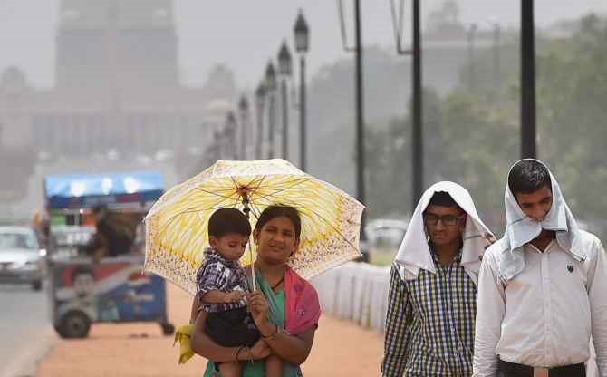 People take protection from the scorching heat on a hot day at Rajpath in New Delhi 