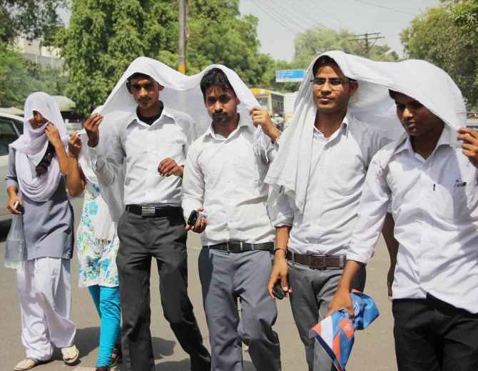 Students protect themselves from the scorching heat on a very hot day in Allahabad