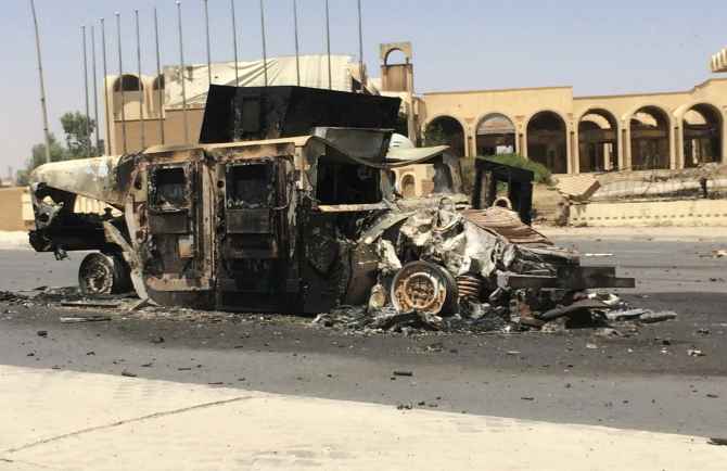 A burnt vehicle belonging to the Iraqi security forces is left on a road a day after insurgents seized control of Mosul 