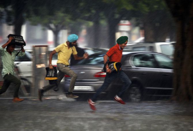 Men run for cover during a heavy rain shower in the northern Indian city of Chandigarh