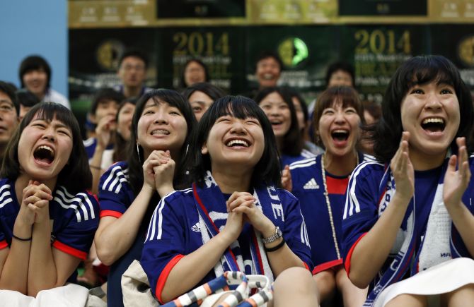 Japanese fans pray as they cheer on their team during their match against Ivory Coast at the FIFA World Cup in Brazil.