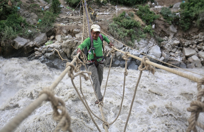 A man crosses a rope bridge over the Alaknanda river during rescue operations in Govindghat in Uttarakhand in this photograph taken on June 23, 2013.