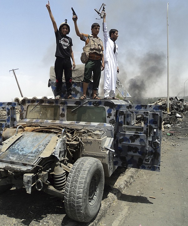 Gunmen celebrate near a vehicle belonging to Iraqi security forces in the northern Iraq city of Mosul