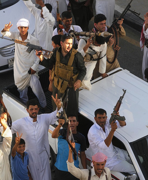 Tribal fighters shout slogans as they carry weapons during a parade on the streets of Najaf, south of Baghdad