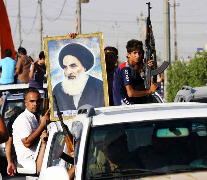 Volunteers with the Iraqi army fighting against Sunni ISIS militants, carry weapons and a portrait of Grand Ayatollah Ali al-Sistani during a parade in Baghdad