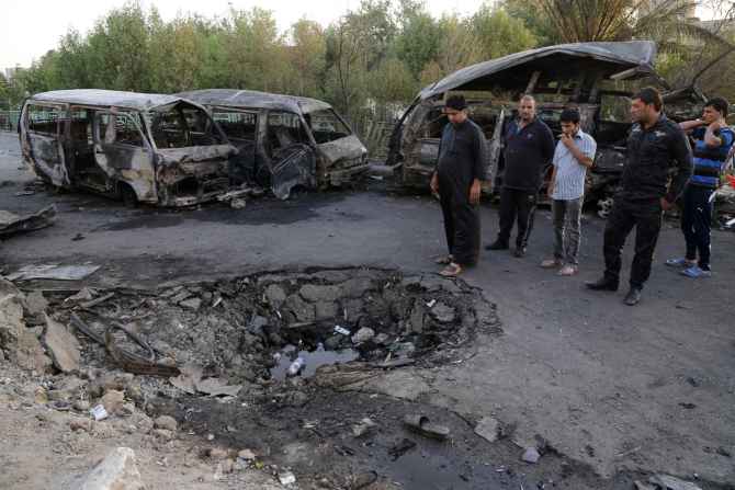 People gather at the site of an ISIS-orchestrated car bomb attack in Baghdad's Sadr City