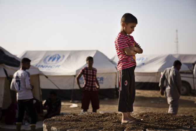 A boy, who fled from the violence in Mosul, stands near tents in a camp for internally displaced people on the outskirts of Erbil in Iraq's Kurdistan 