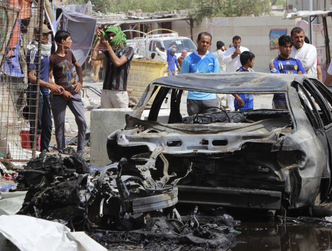 People look at the cars, which were burnt by the Sunni rebels.