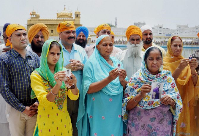 Family members of the Indians who are abducted in Mosul show their pictures outside the Golden Temple, Amritsar