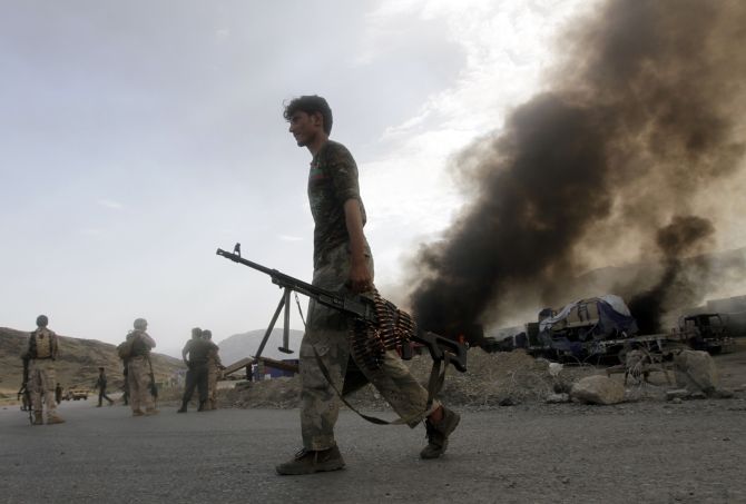 Afghan security forces leave the site of burning NATO supply trucks after an attack by militants in the Torkham area near the Pakistani-Afghan in Nangarhar Province