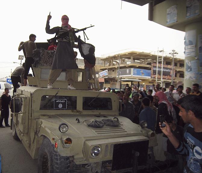 ISIS fighters celebrate on vehicles taken from Iraqi security forces on a main street in Fallujah, west of Baghdad