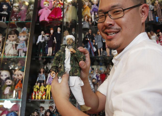 A vendor holds up an Osama bin Laden doll, which became very popular after his death.